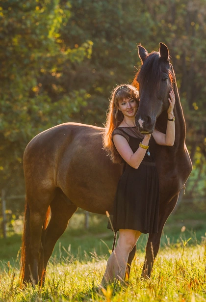 Frau mit dunklem Pferd im Abendlicht