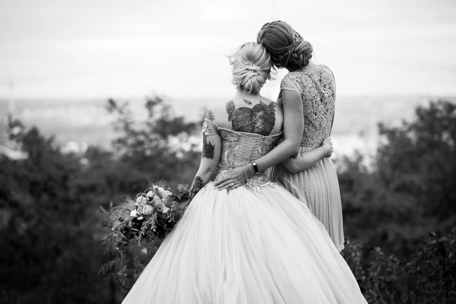 Zwei Frauen in Hochzeitskleidern mit Blick in die Ferne, schwarzweiß mit dezenter warmer Tonung